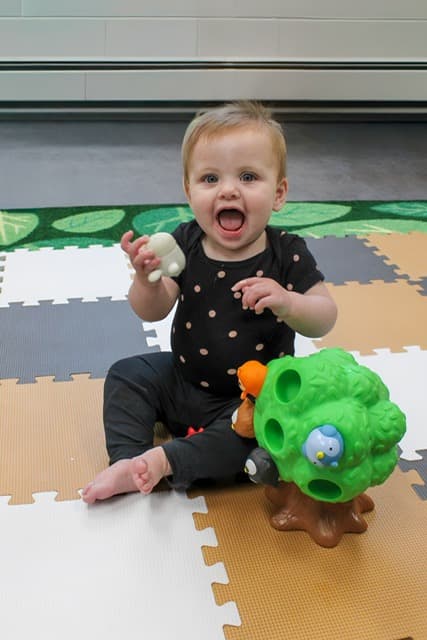 An infant playing with a toy at Rainbow Years